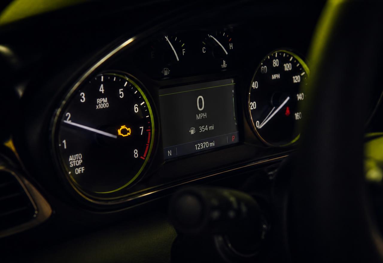 Night-time close-up of an instrument cluster with an amber check engine indicator lit